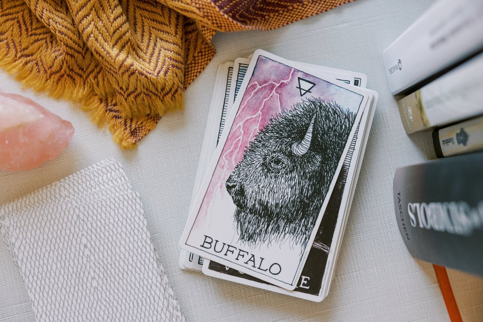 Une carte d'oracle posée sur un jeu, à côté d'un quartz rose