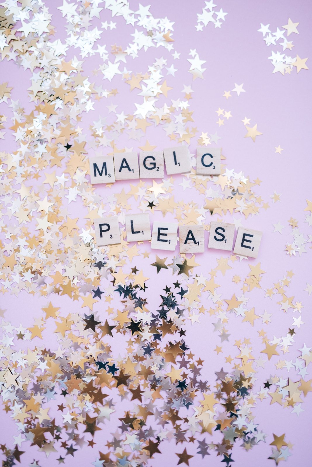 Les mots Magic please en lettres de Scrabble, parmi des confettis étoilés